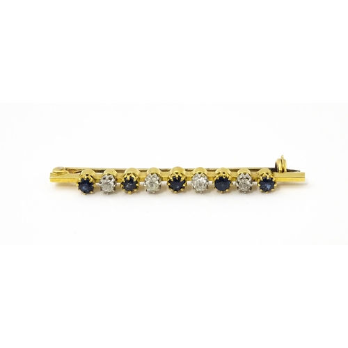 749 - A gold bar brooch with platinum set diamonds, and blue stones. Approx. 2