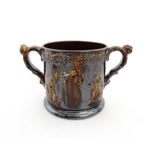 68 - A large Staffordshire treacle glazed frog loving cup decorated in relief with depictions of Nelson, ... 