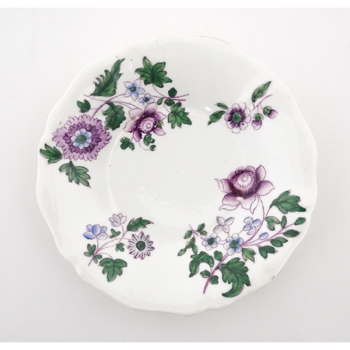 73 - A pair of Lowestoft style saucers decorated with purple and green flowers. Numbered to rim of bases ... 