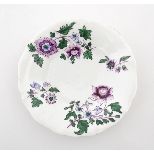 73 - A pair of Lowestoft style saucers decorated with purple and green flowers. Numbered to rim of bases ... 