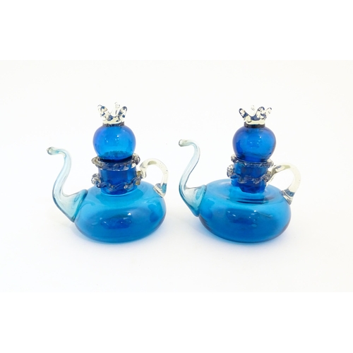 183 - An unusual pair of turquoise glass oil / vinegar bottles of teapot form, the lids surmounted by styl... 