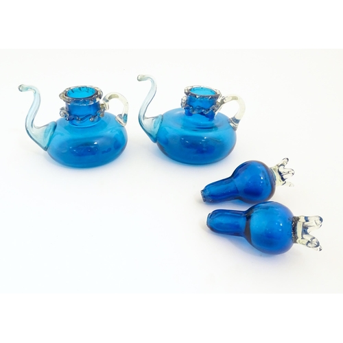 183 - An unusual pair of turquoise glass oil / vinegar bottles of teapot form, the lids surmounted by styl... 