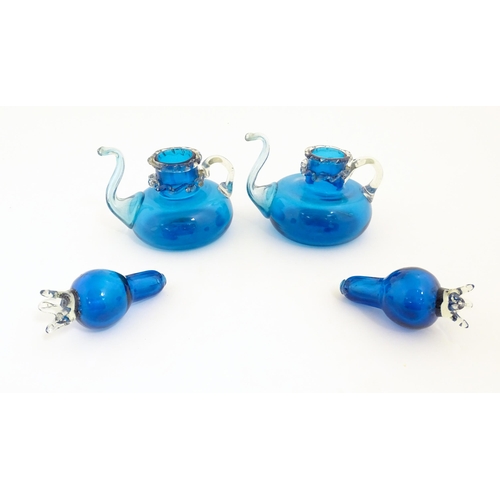 183 - An unusual pair of turquoise glass oil / vinegar bottles of teapot form, the lids surmounted by styl... 