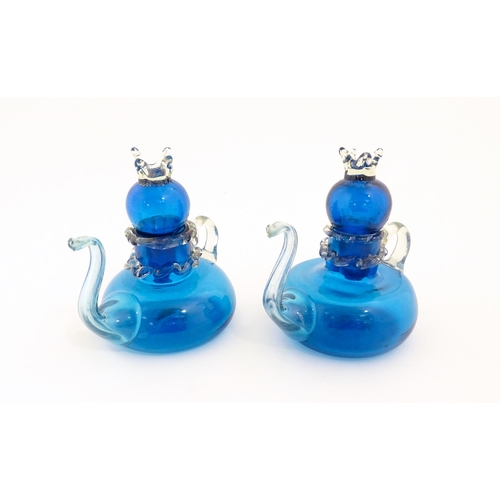 183 - An unusual pair of turquoise glass oil / vinegar bottles of teapot form, the lids surmounted by styl... 