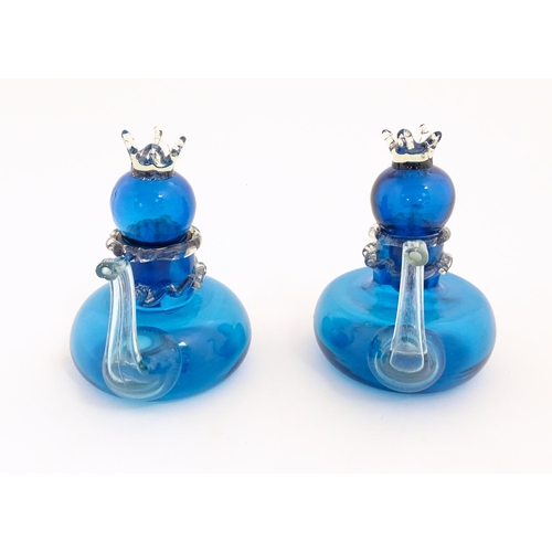 183 - An unusual pair of turquoise glass oil / vinegar bottles of teapot form, the lids surmounted by styl... 