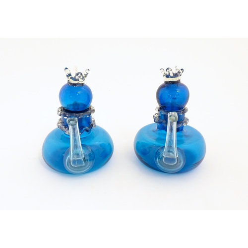 183 - An unusual pair of turquoise glass oil / vinegar bottles of teapot form, the lids surmounted by styl... 