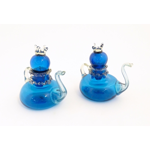 183 - An unusual pair of turquoise glass oil / vinegar bottles of teapot form, the lids surmounted by styl... 