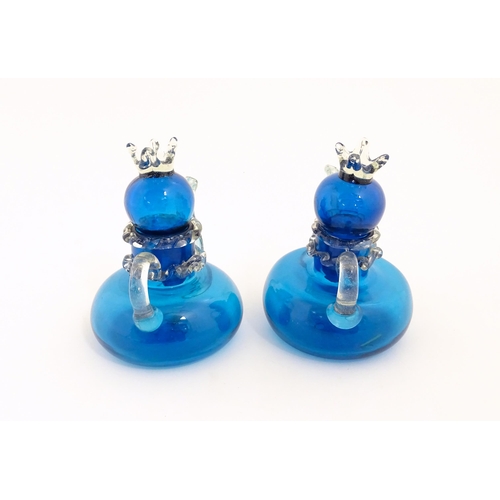 183 - An unusual pair of turquoise glass oil / vinegar bottles of teapot form, the lids surmounted by styl... 