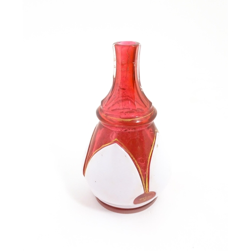 216 - A small Bohemian style red and white glass bottle vase with gilt highlights. Approx. 3 3/4