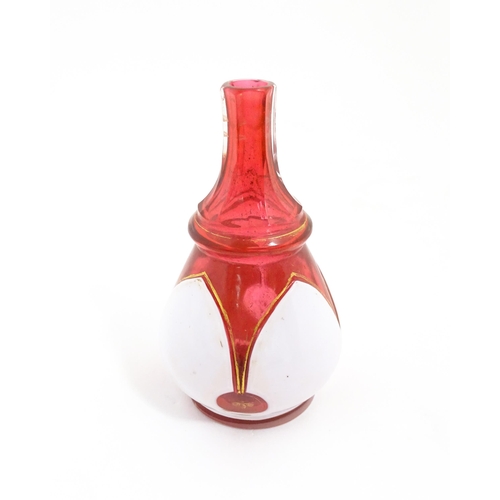 216 - A small Bohemian style red and white glass bottle vase with gilt highlights. Approx. 3 3/4