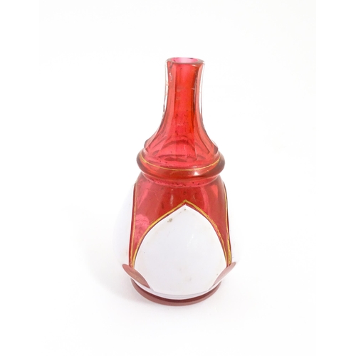 216 - A small Bohemian style red and white glass bottle vase with gilt highlights. Approx. 3 3/4