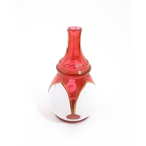 216 - A small Bohemian style red and white glass bottle vase with gilt highlights. Approx. 3 3/4