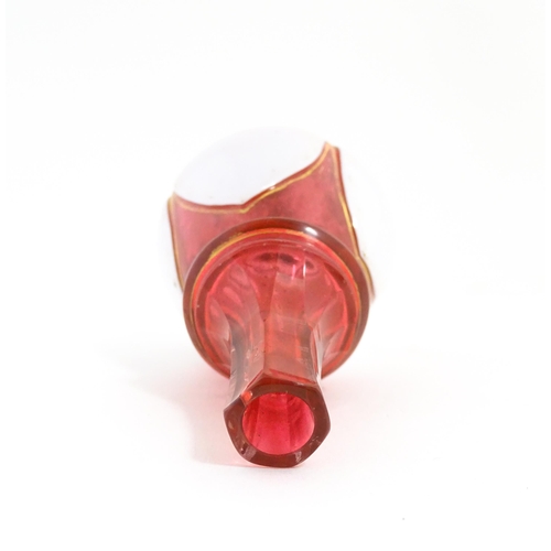 216 - A small Bohemian style red and white glass bottle vase with gilt highlights. Approx. 3 3/4