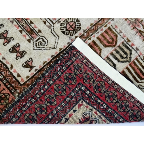 1380 - Carpet / Rug: A beige ground rug with repeated motifs worked in salmon pink, brown and beige, with b... 