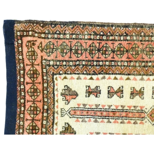 1380 - Carpet / Rug: A beige ground rug with repeated motifs worked in salmon pink, brown and beige, with b... 