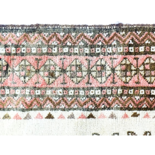 1380 - Carpet / Rug: A beige ground rug with repeated motifs worked in salmon pink, brown and beige, with b... 