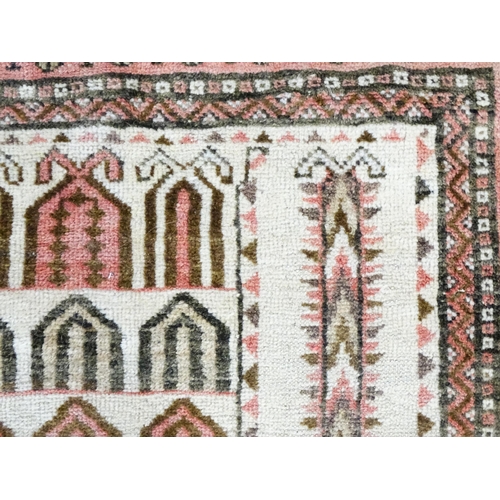 1380 - Carpet / Rug: A beige ground rug with repeated motifs worked in salmon pink, brown and beige, with b... 