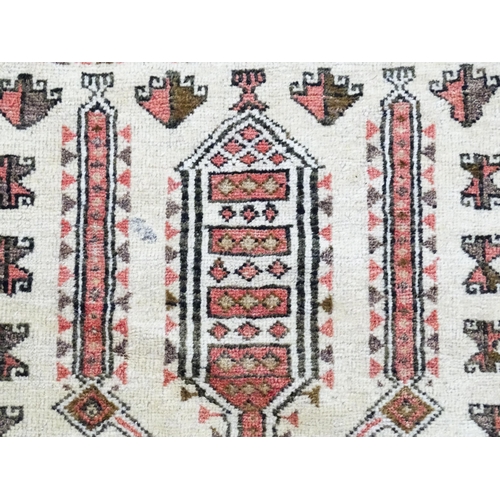 1380 - Carpet / Rug: A beige ground rug with repeated motifs worked in salmon pink, brown and beige, with b... 