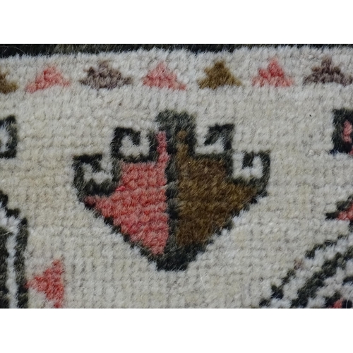 1380 - Carpet / Rug: A beige ground rug with repeated motifs worked in salmon pink, brown and beige, with b... 