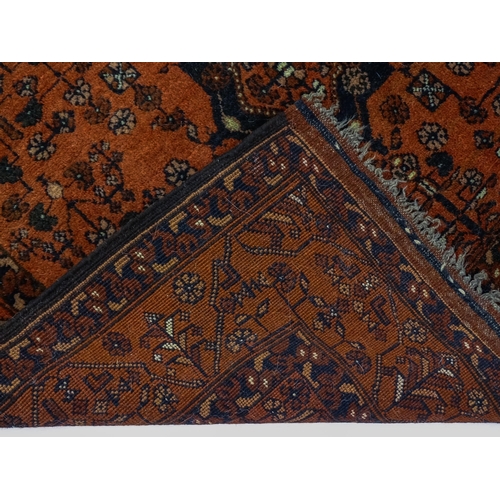 1383 - Carpet / Rug: A red ground rug decorated with floral and foliate detail, further repeated to borders... 