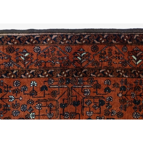 1383 - Carpet / Rug: A red ground rug decorated with floral and foliate detail, further repeated to borders... 