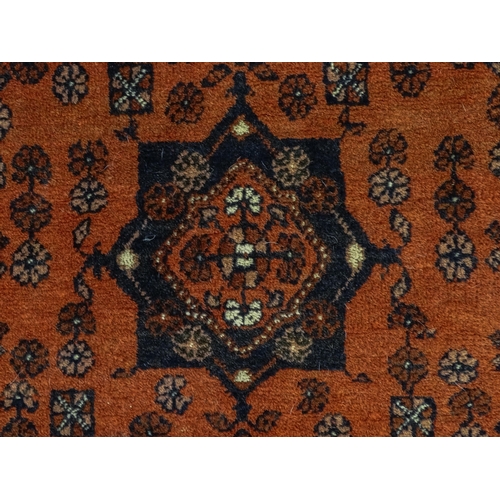 1383 - Carpet / Rug: A red ground rug decorated with floral and foliate detail, further repeated to borders... 