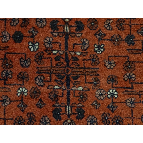 1383 - Carpet / Rug: A red ground rug decorated with floral and foliate detail, further repeated to borders... 