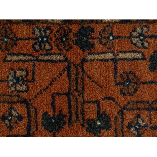 1383 - Carpet / Rug: A red ground rug decorated with floral and foliate detail, further repeated to borders... 