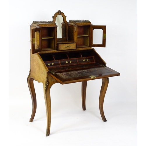 1476 - A 19thC burr walnut Bonheur du jour with a mirrored back stand and flanked by two glazed cabinets wi... 