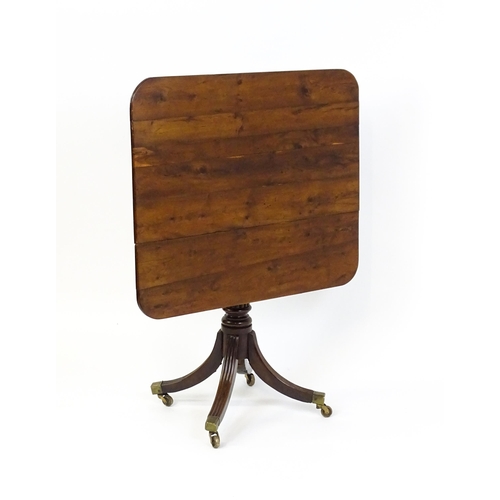 1488 - A 19thC tilt top occasional table with yew wood planked top above a reeded mahogany pedestal and fou... 