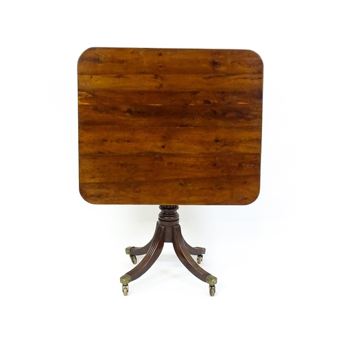 1488 - A 19thC tilt top occasional table with yew wood planked top above a reeded mahogany pedestal and fou... 