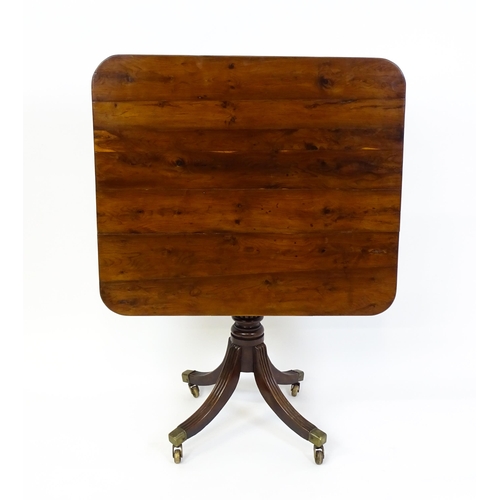 1488 - A 19thC tilt top occasional table with yew wood planked top above a reeded mahogany pedestal and fou... 