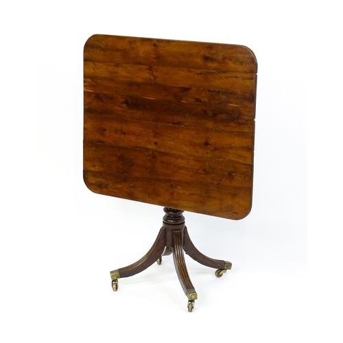 1488 - A 19thC tilt top occasional table with yew wood planked top above a reeded mahogany pedestal and fou... 