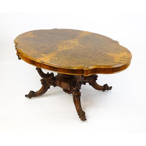 1496 - A 19thC burr walnut centre table with a moulded top above four acanthus carved supports, a large tur... 