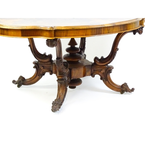 1496 - A 19thC burr walnut centre table with a moulded top above four acanthus carved supports, a large tur... 