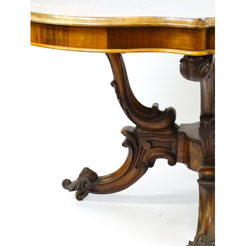 1496 - A 19thC burr walnut centre table with a moulded top above four acanthus carved supports, a large tur... 