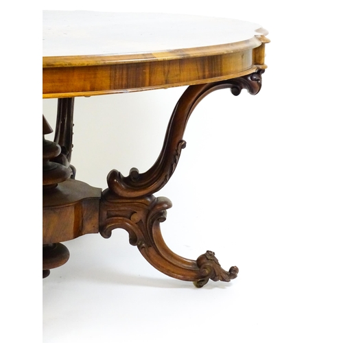 1496 - A 19thC burr walnut centre table with a moulded top above four acanthus carved supports, a large tur... 