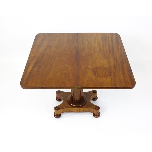 1504 - A 19thC mahogany tea table / card table with a hinged, revolving top above a turned pedestal and app... 