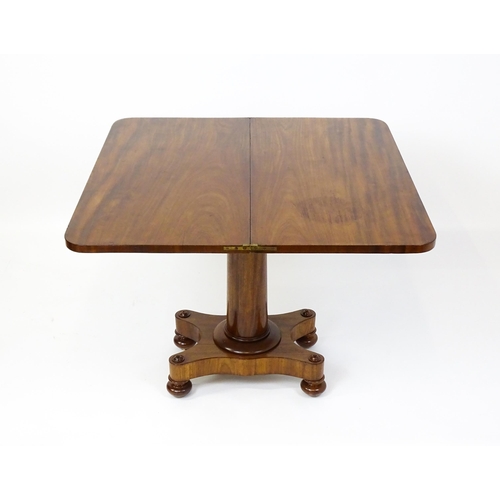 1504 - A 19thC mahogany tea table / card table with a hinged, revolving top above a turned pedestal and app... 