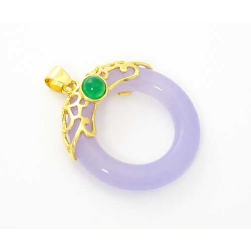 754 - A pendant with gilt metal mounts and purple coloured jade like ring detail. 1 1/2