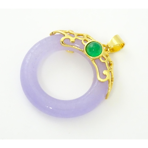 754 - A pendant with gilt metal mounts and purple coloured jade like ring detail. 1 1/2