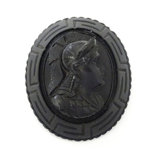 761 - A Victorian Whitby jet cameo brooch depicting the head of a Roman solider, within a Greek key mount.... 