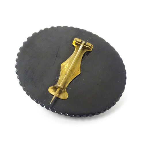 761 - A Victorian Whitby jet cameo brooch depicting the head of a Roman solider, within a Greek key mount.... 