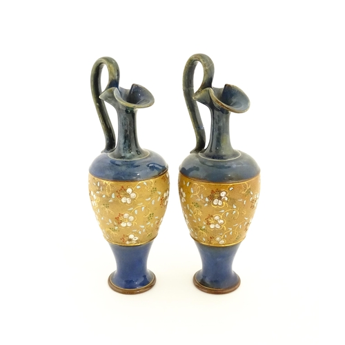 127 - A pair of Royal Doulton stoneware jugs of Classical ewer form with floral and foliate decoration. Ma... 