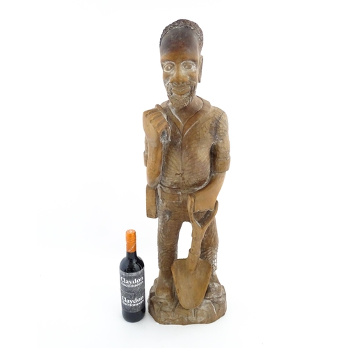 1131 - Ethnographic / Native / Tribal: An African carved wood figure modelled as a male farmer with a spade... 