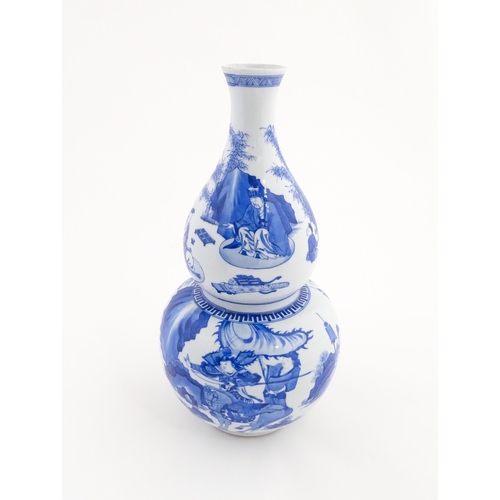 22 - A Chinese blue and white double gourd vase decorated with figures in a landscape. Approx. 16 1/4