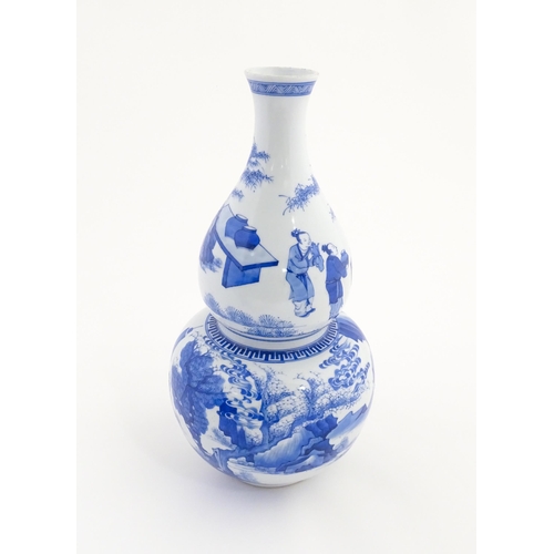 22 - A Chinese blue and white double gourd vase decorated with figures in a landscape. Approx. 16 1/4