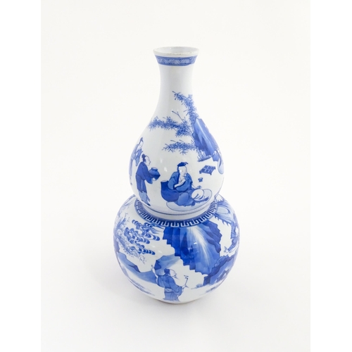 22 - A Chinese blue and white double gourd vase decorated with figures in a landscape. Approx. 16 1/4