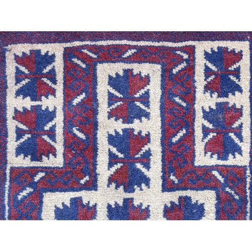 1369 - Carpet / Rug : A red, blue and cream ground rug with repeating geometric motifs. Approx. 55