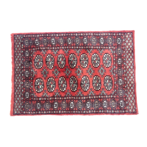 1370 - Carpet / Rug : A Pakistan wool red ground rug decorated with repeating geometric motifs with further... 